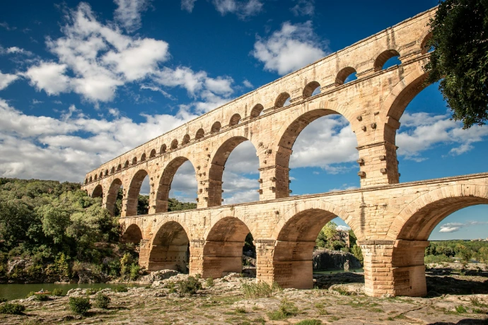 A large stone bridge over a river under a blue sky